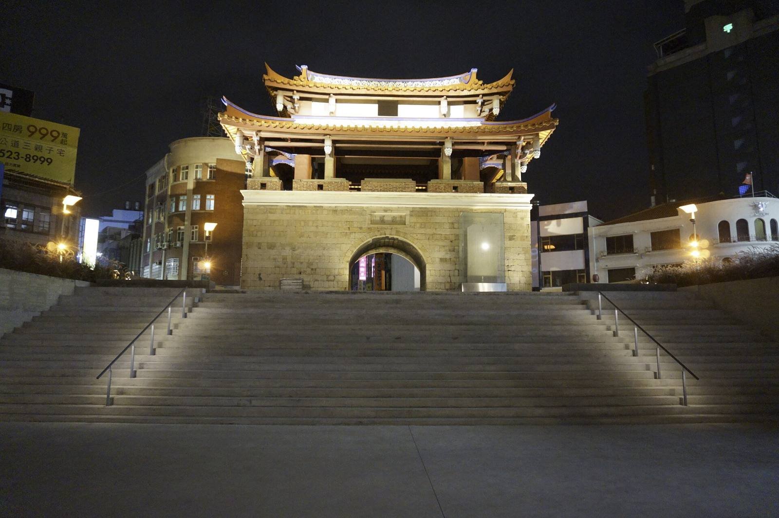 The East Gate of Hsinchu lit up at night, with wide steps leading up to the gate tower