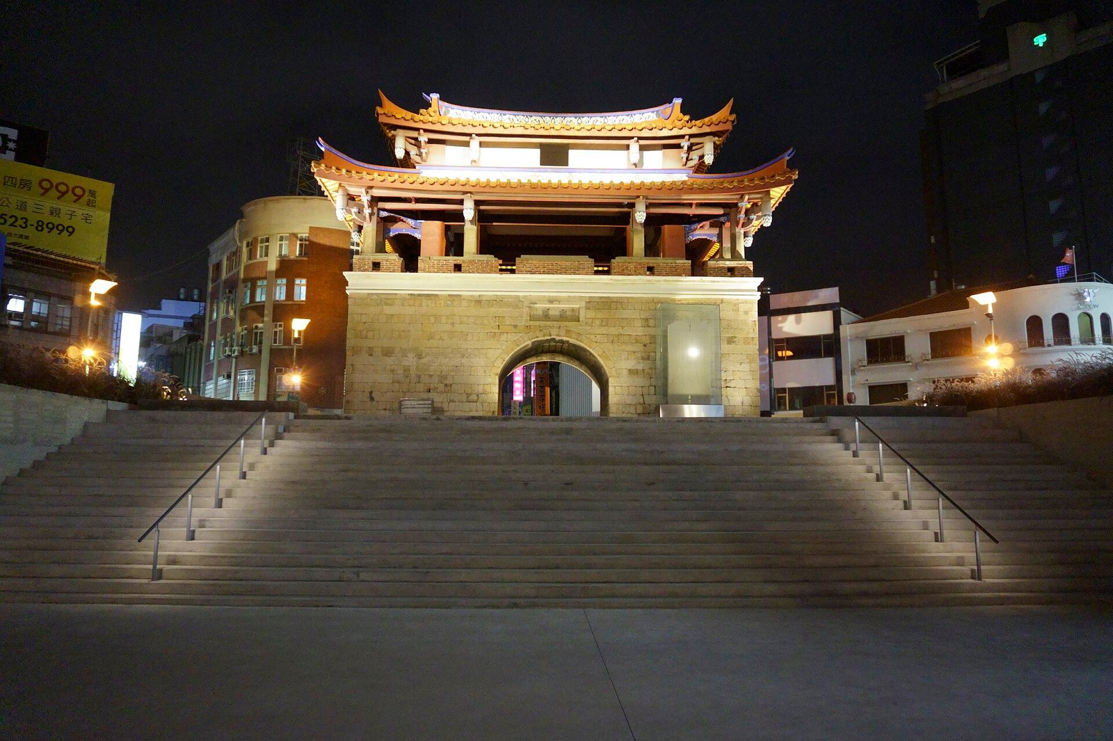 The East Gate of Hsinchu lit up at night, with wide steps leading up to the gate tower