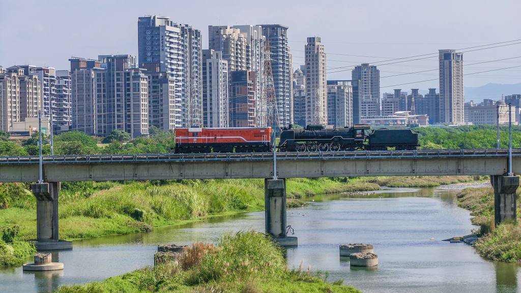 The tower blocks of Zhubei behind a river, with a train crossing a bridge