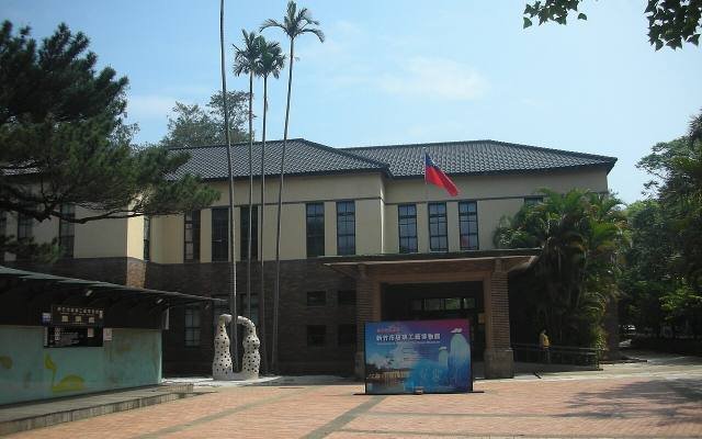 The low Japanese-era building of the Hsinchu City Glass Museum among palm trees