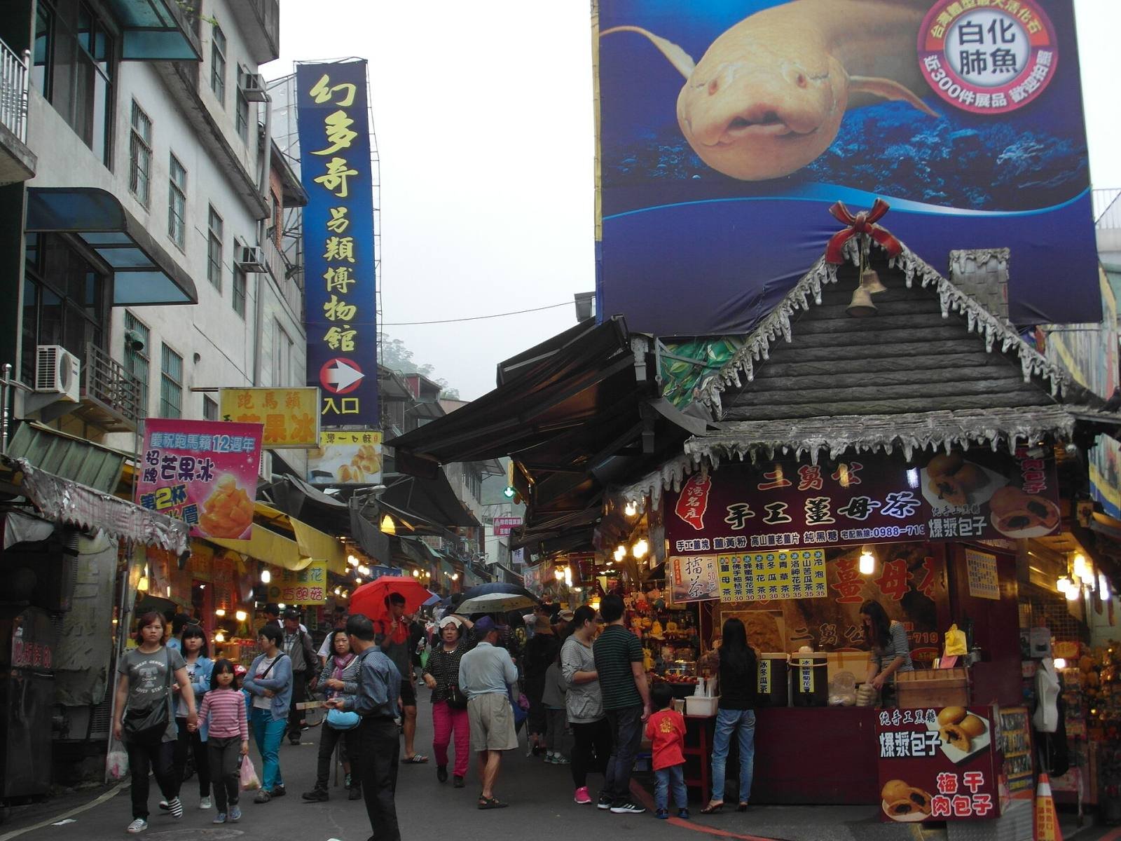Shops and food stalls under a pointed wooden roof on Neiwan Old Street