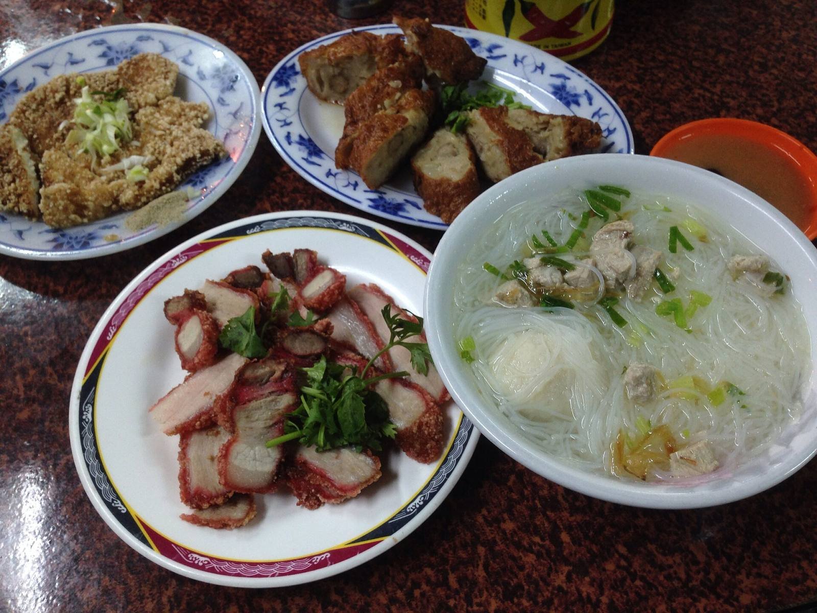 Rice noodle soup, roast pork and fried snacks on blue and white plates