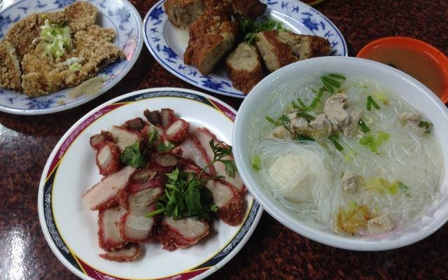 Rice noodle soup, roast pork and fried snacks on blue and white plates
