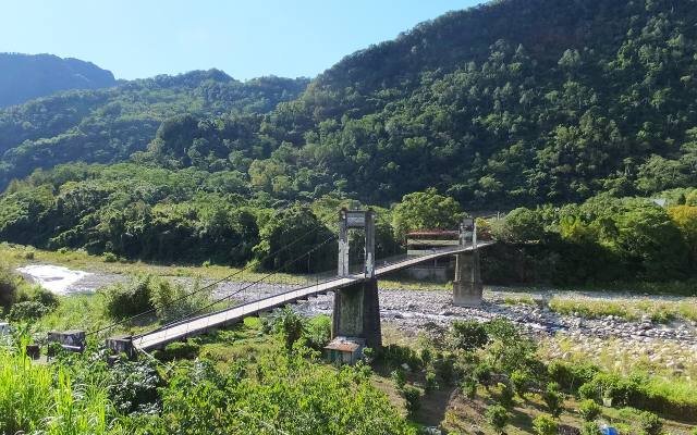 The Neiwan suspension bridge across a wide river valley, below forested hills